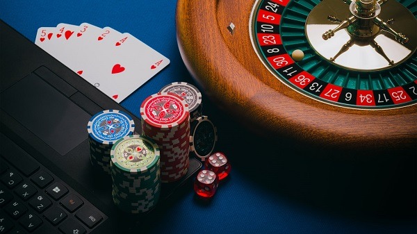 roulette, poker chips, dice, and cards beside a laptop