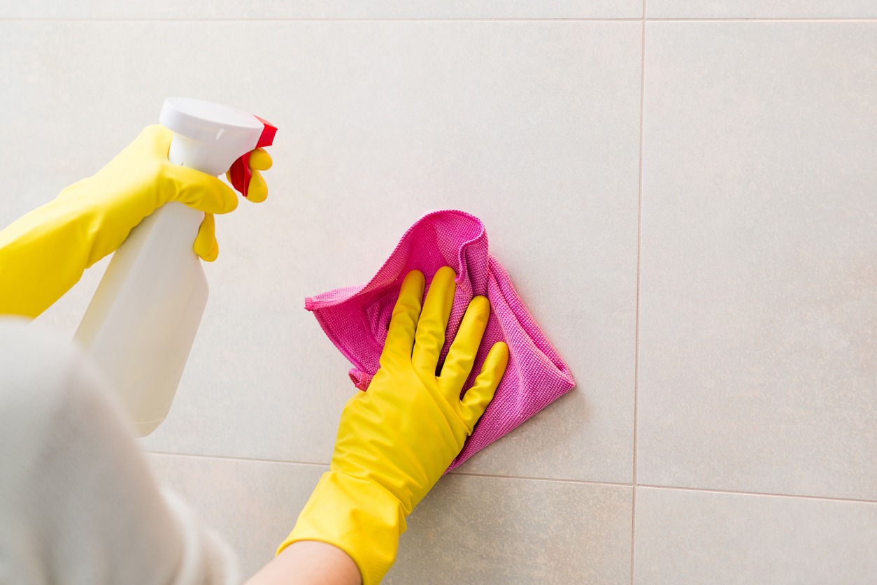 cleaning tiles in bathroom with pink cloth