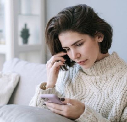 a-woman-in-white-knitted-sweater-using-a-cellphone