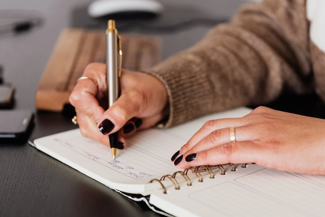 woman writing down notes in diary